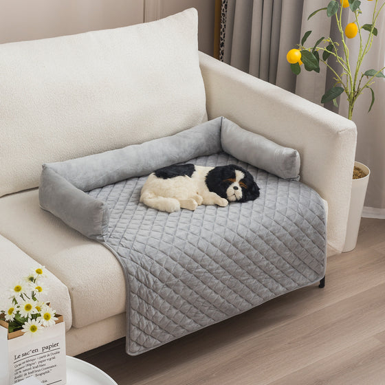 Hellgrauer Plüsch-Sofaschoner mit Randrolle auf einem hellen Sofa, kleiner Hund liegt darauf