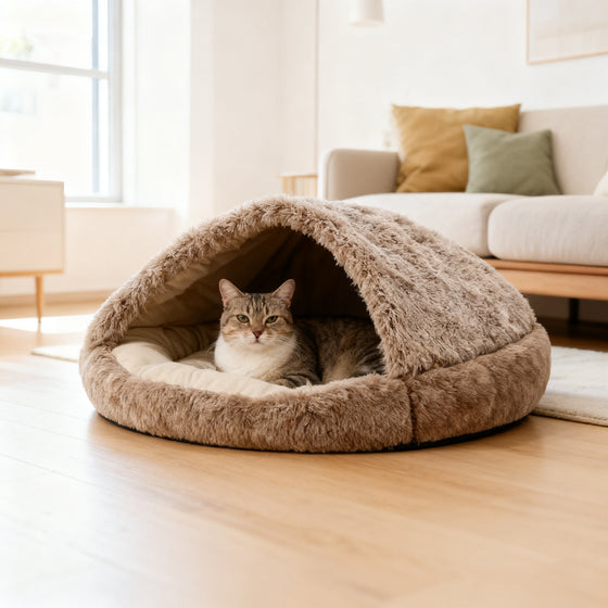 Katze liegt in einem halboffenen Plüsch Kuschelnest in Beige mit umklappbarer Abdeckung